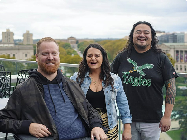 A picture of the three hosts of Delicious City Podcast, a podcast performing live at the Philadelphia Inquirer Food Fest, on November 15th, 2025